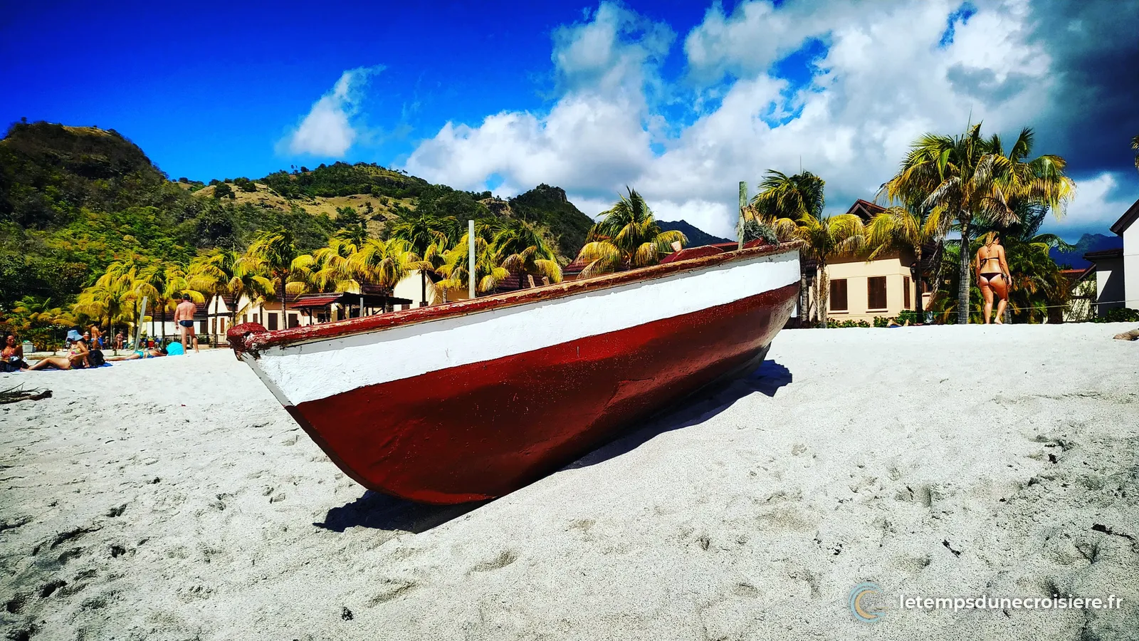 Une barque rouge et blanche échouée sur le sable, à Saint-Vincent